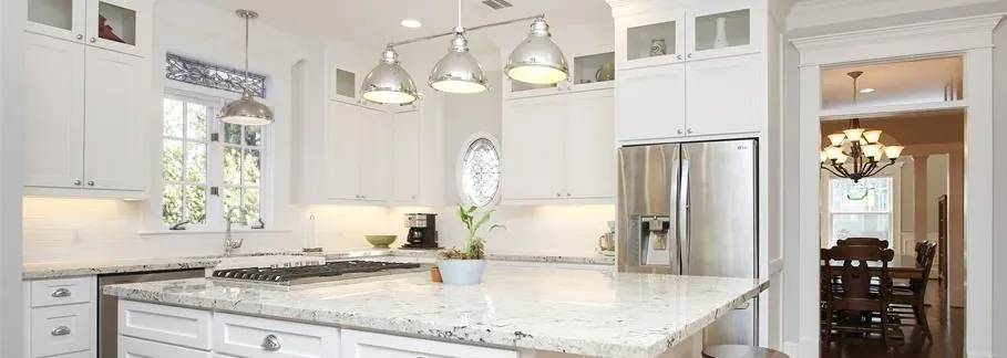 Before: the 2000s kitchen with white cabinets, a granite island and chrome pendants