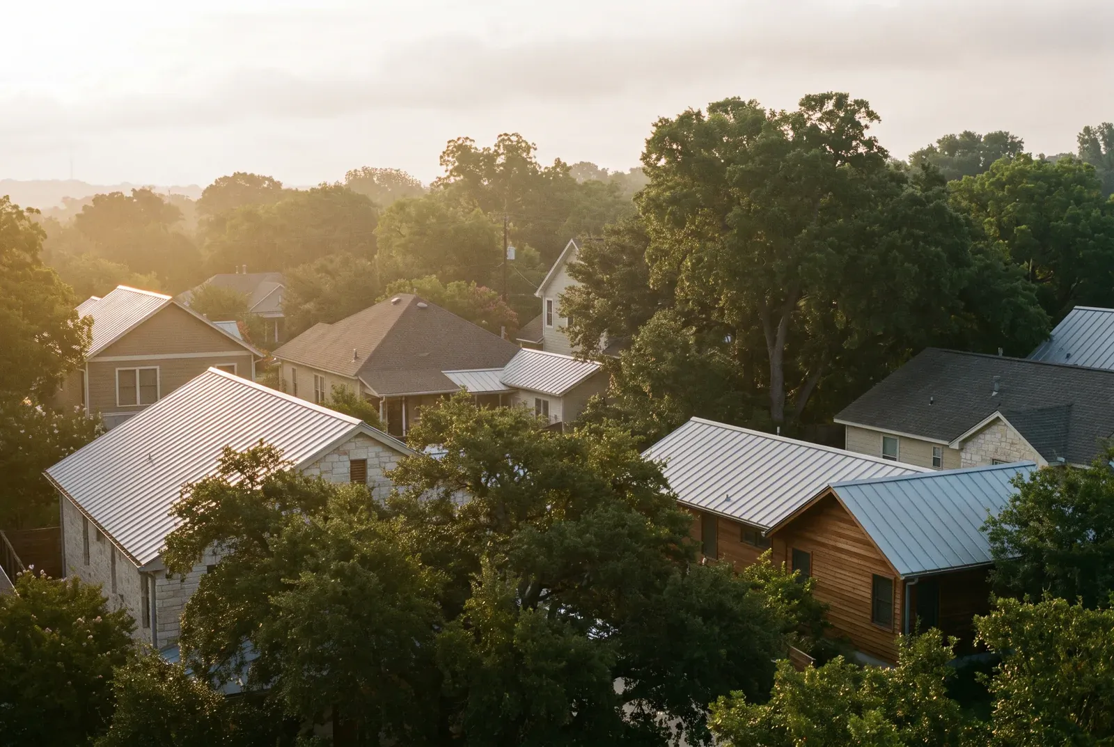 Hazy morning light over tree-lined Austin rooftops on a humid summer day